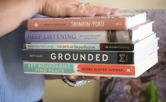 Werkwijze. Twee handen houden een stapel boeken vast