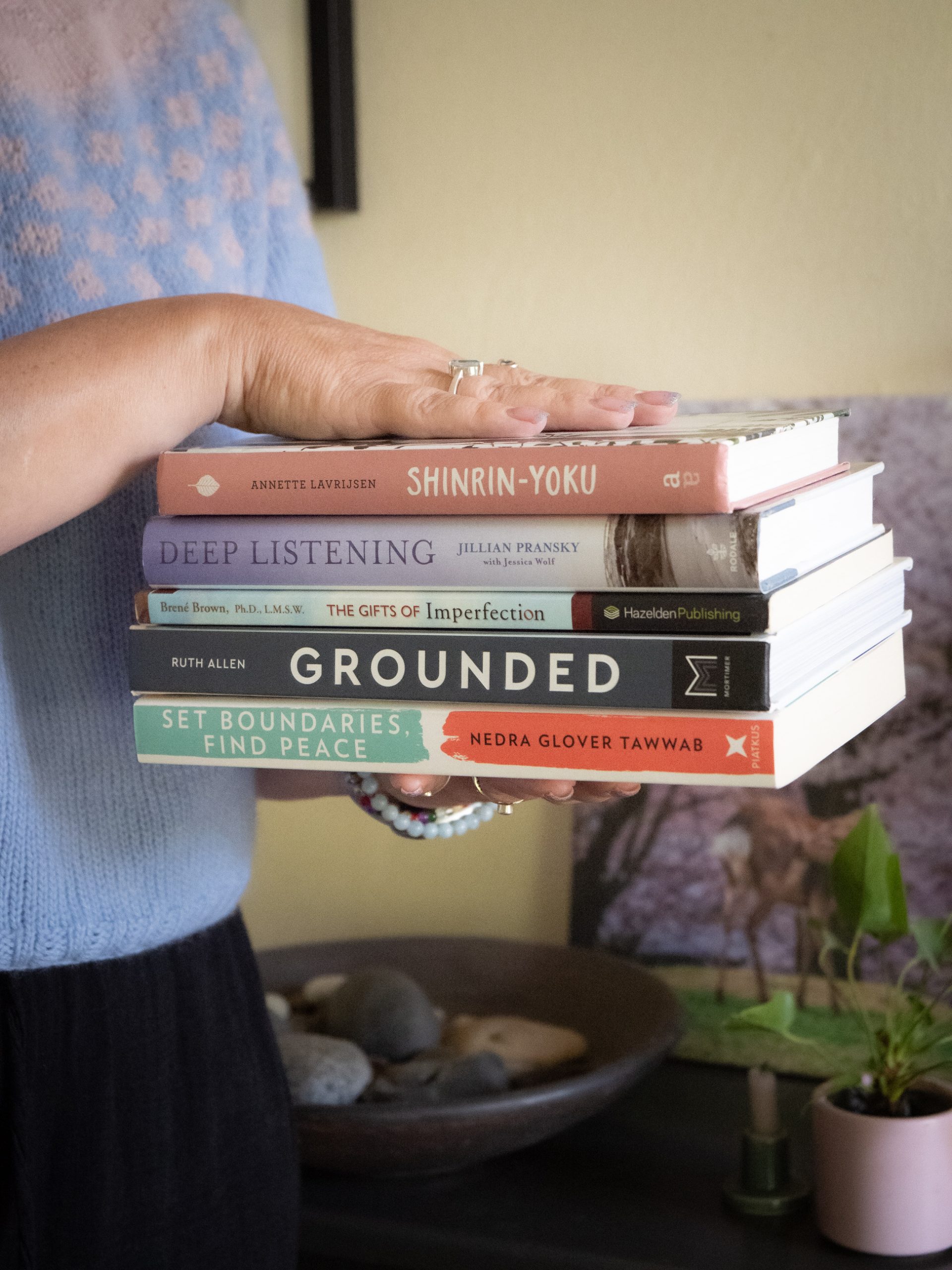 Werkwijze. Twee handen houden een stapel boeken vast